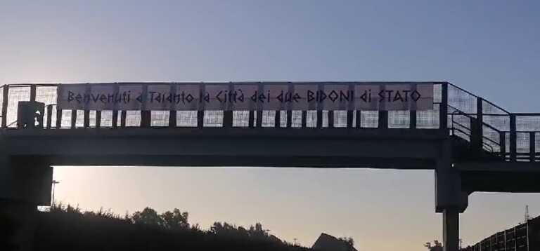 Striscione indotto ex Ilva, ‘Città dei due bidoni di Stato’. La scritta sulla statale 100 – VIDEO